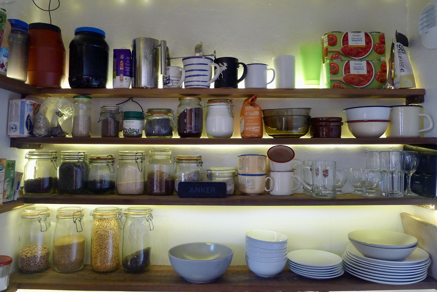 Kitchen shelves stocked with crockery, glasses and food containers
